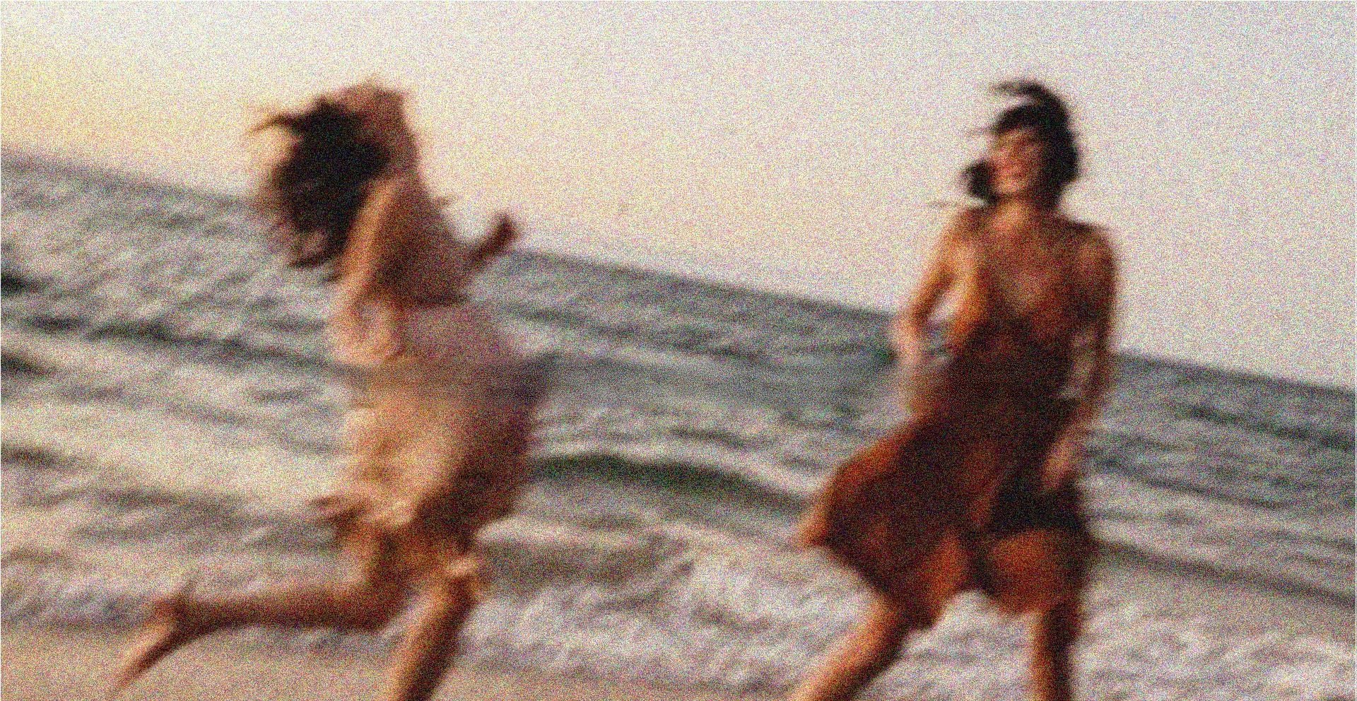 Duas mulheres correndo e rindo na beira do mar