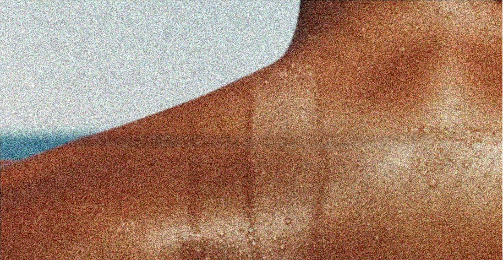Ombro bronzeado com gotas de suor, céu ao fundo